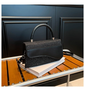 Détail du sac à main noir à paillettes avec rabat ondulé et poignée argentée chic