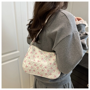 Detail of white underarm bag featuring pink bow patterns and textured embossed fabric