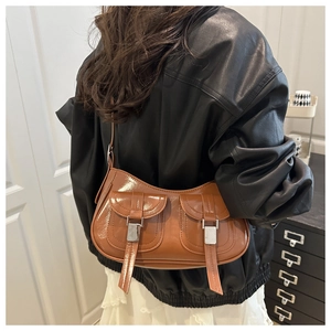 Brown glossy faux leather baguette bag shown on a model from a side-back angle