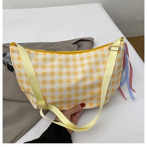 Detail of yellow plaid canvas crossbody bag with adjustable strap and colorful braided knot