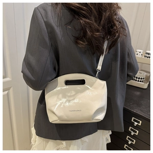 Detail of cream patent leather mini bag with cutout handle and glossy mirror finish
