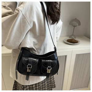 Detail of a vintage-style black leather shoulder bag with dual front pockets and silver buckles