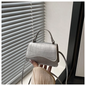Gros plan du mini sac argenté avec motif crocodile et détail de la fine bandoulière