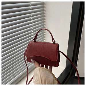 Détail du mini sac bordeaux en relief crocodile avec rabat ondulé et bijoux argentés