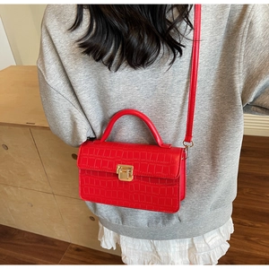 Detail of red crocodile texture crossbody bag with gold square lock on model