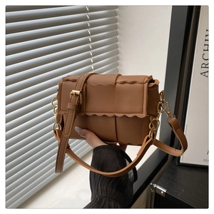 Detailed view of brown woven leather bag featuring scalloped edge and gold chain strap