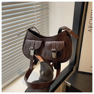 Detail of dark brown faux leather crescent bag featuring dual front pockets and silver buckles