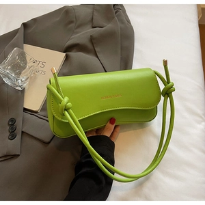 Detail of bright green underarm bag with knot strap and gold Fashion & Bags logo