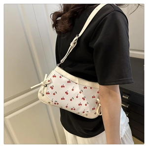 Detail shot of small white shoulder bag with cherry print and bow knot strap