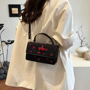 Chic black crossbody square bag with cherry print and crystal charm on white shirt model