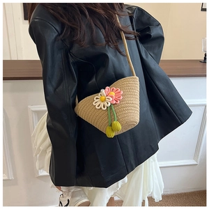Detailaufnahme einer Strohtasche mit 3D-Häkelblumen auf einem schwarzen Lederblazer