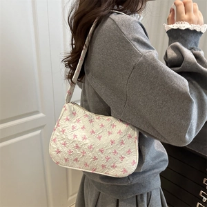 White shoulder bag with pink bows and textured floral design shown on model