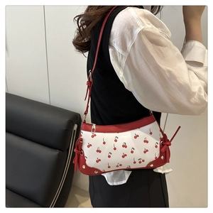 Gros plan sur le motif cerise et le détail du nœud rouge sur le côté du sac à main