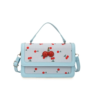 Blue leather and cherry print crossbody flap bag with rhinestone cherry charm on white background