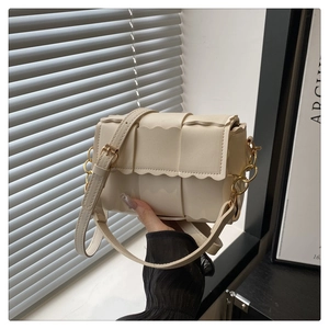 Close-up of cream crossbody bag featuring unique wavy woven texture and gold chain detail