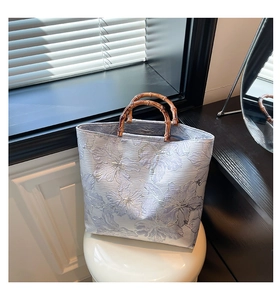 Detail of lilac tote bag with 3D floral relief texture and bamboo top handle