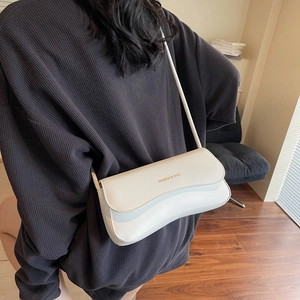 Minimalist white underarm bag with wavy flap edge and gold lettering for women
