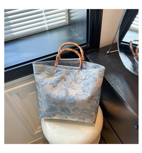 Detailed close-up of light blue floral jacquard fabric with a vintage bamboo handle