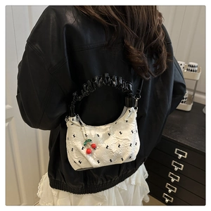 Close-up of white ripple texture dumpling bag with black handle and cherry charm
