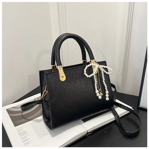 Detail of black glitter leather handbag with pearl bow charm and gold hardware
