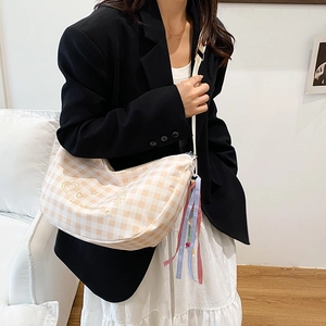 Chic beige plaid canvas hobo bag with heart embroidery and decorative ribbon on model