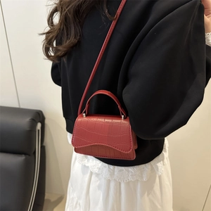 Mini sac à main rouge motif crocodile avec bandoulière porté par un mannequin chic
