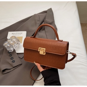 Close-up of brown crocodile texture leather bag with elegant metallic buckle detail