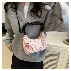 Borsa a tracolla plissettata rosa con ricami di fiocchi neri e dettaglio charm ciliegia