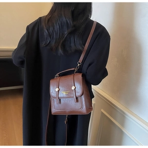 Detailed view of a vintage brown leather backpack with gold hardware worn by a model
