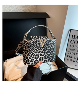 Close-up of leopard print handbag with gold V-buckle and dual straps in a gift box