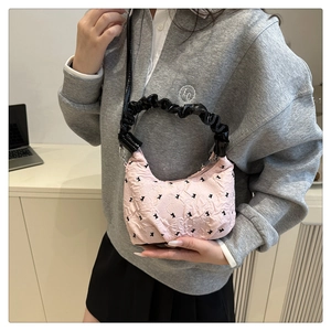 Close-up of pink pleated dumpling bag with black rabbit pattern and glossy top handle