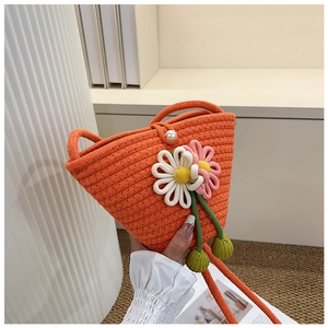 Detail der orangefarbenen Flecht-Beuteltasche mit 3D-Blumen und Perlenverschluss