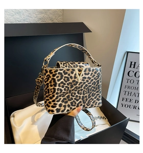 Detail view of leopard print crossbody bag with metallic V-shaped buckle in gift box