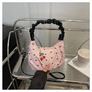Pink quilted dumpling bag with cherry charm and black bow embroidery detail