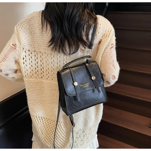 Detail of vintage black faux leather backpack with gold buckles on a wooden staircase
