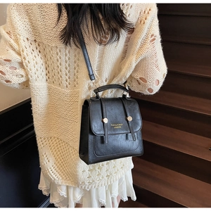 Detail of vintage black matte leather backpack with gold buckles and fine texture