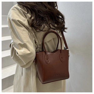 Detail of dark brown leather bucket bag with embossed logo and adjustable shoulder strap