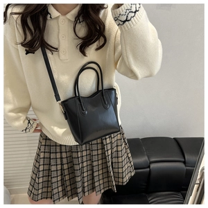 Detail of minimalist black matte leather bucket bag with top handle and crossbody strap