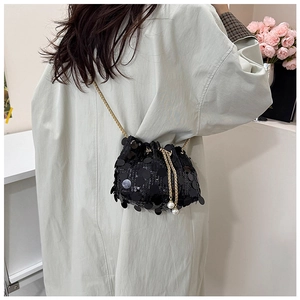 Detail of black sequin bucket bag with gold chain strap and pearl drawstring tassels