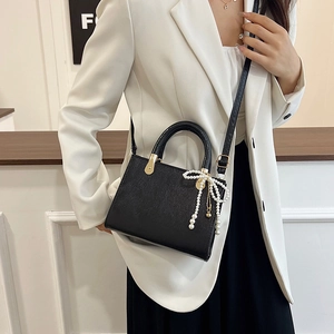 Elegant black faux leather crossbody bag with pearl bow and gold hardware detail