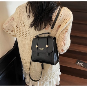 Detail of black leather backpack with gold buckle and adjustable strap on a model
