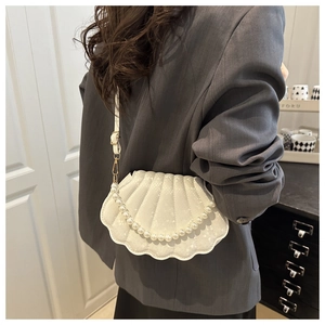 Detail of white shell-shaped shoulder bag with pearl handle and textured leather finish