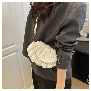 White shell shape crossbody bag with pearl chain and crocodile texture on model