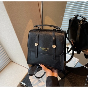 Detail of a vintage black leather backpack showing the gold buckle and textured finish
