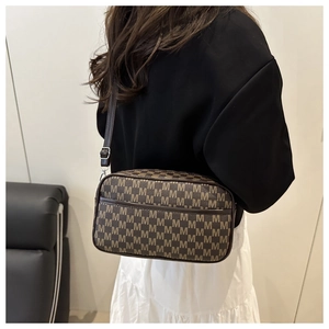 Detail of crossbody bag showing brown monogram texture and checkerboard pattern on shoulder