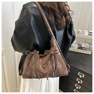 Detail of brown shoulder bag with decorative bows and stylish zippers on the glossy surface