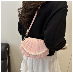 Detailed view of pink shell-shaped crossbody bag with pearl strap and snake texture