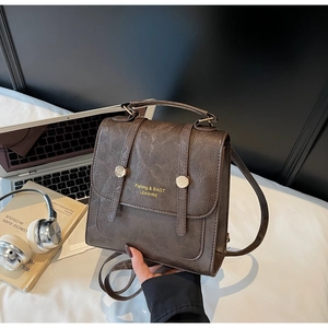 Detailed view of vintage brown mini backpack with cracked leather texture and gold studs