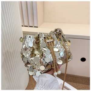 Detail of silver sequin bucket bag featuring pearl charms and a gold chain strap