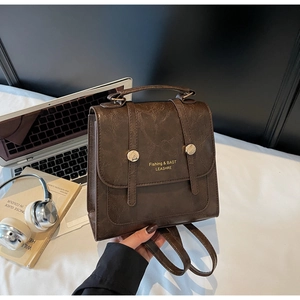 Detail of dark brown vintage faux leather mini backpack with polished texture and metal buckles